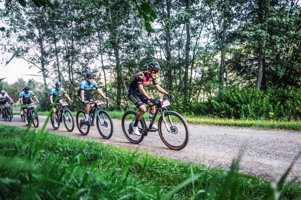 Mehrere Mountainbiker fahren in einer Gruppe auf einem Schotterweg durch den Wald beim Schwarzwald Bike Marathon 2023