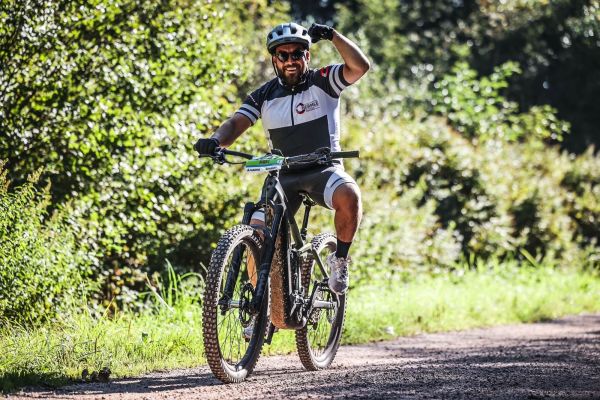 Mountainbiker lächelt und hebt die Faust auf einem Waldweg beim Schwarzwald Bike Marathon 2023