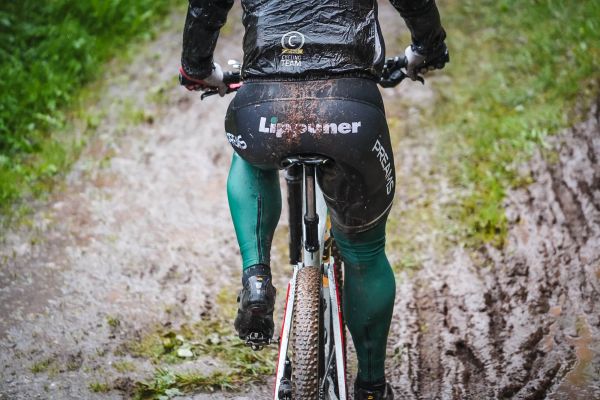 Nahaufnahme von hinten: verschlammte Kleidung und Reifen auf schlammiger Strecke